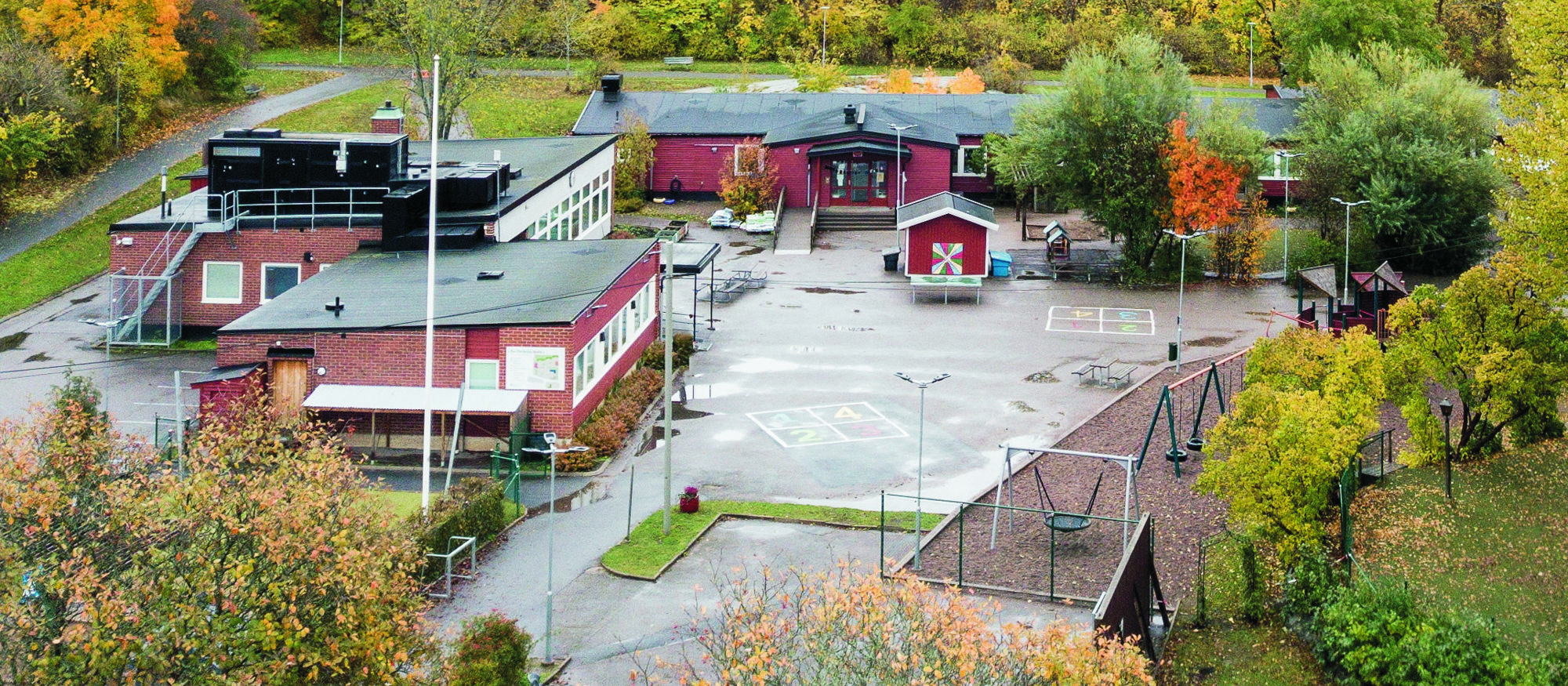 Bo skola. Ingång till röd träbyggnad med vimplar och ballonger