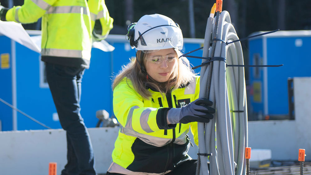 Medarbetare på Veitech arbetar med ett rör, två kollegor står i bakgrunden och tittar på en ritning.