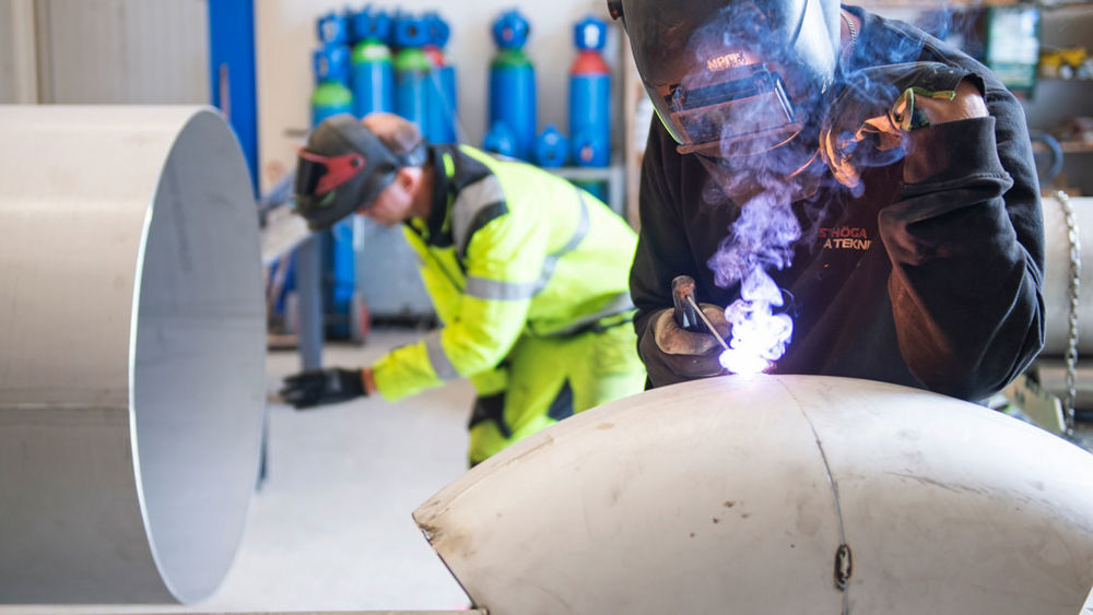 Närbild på en man som svetsar ett rör.