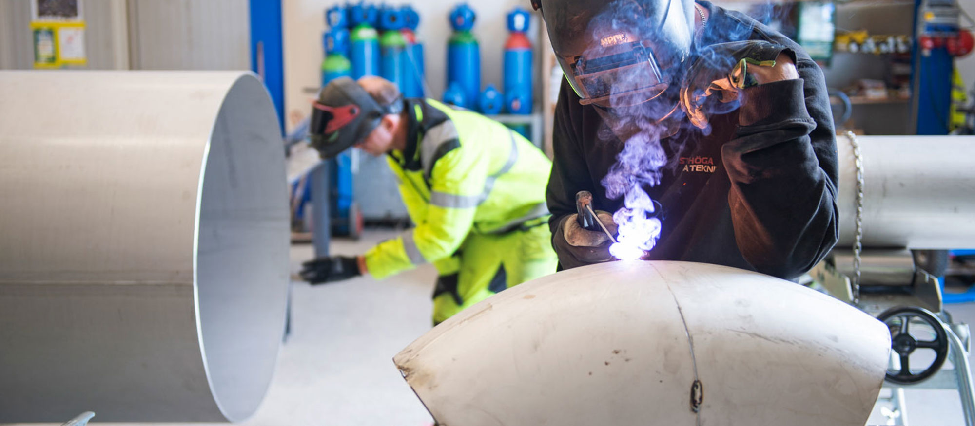Närbild på en man som svetsar ett rör.