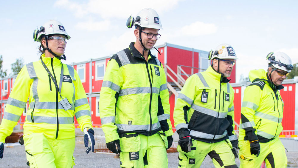 Fyra medarbetare på Veitech utomhus på en byggarbetsplats.