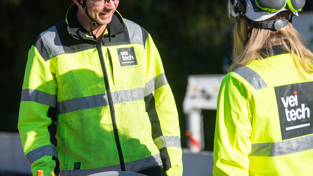 Två medarbetare på Veitech pratar med varandra utomhus.