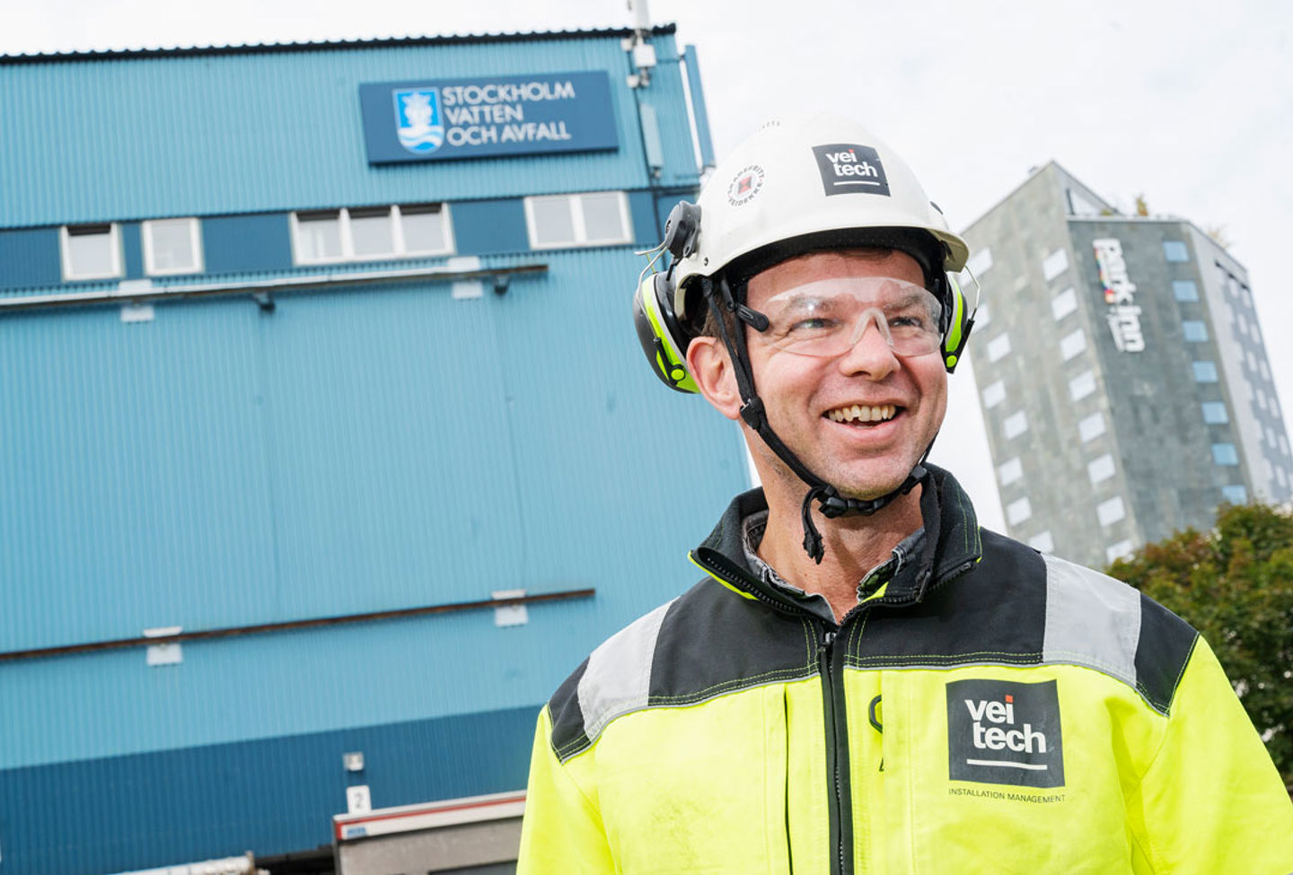 Leende man i bygghjälm och varseljacka.